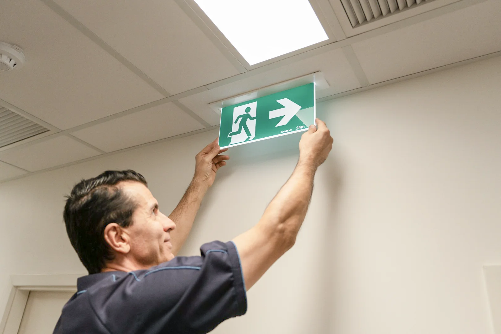 Emergency exit sign being tested in a commercial hallway